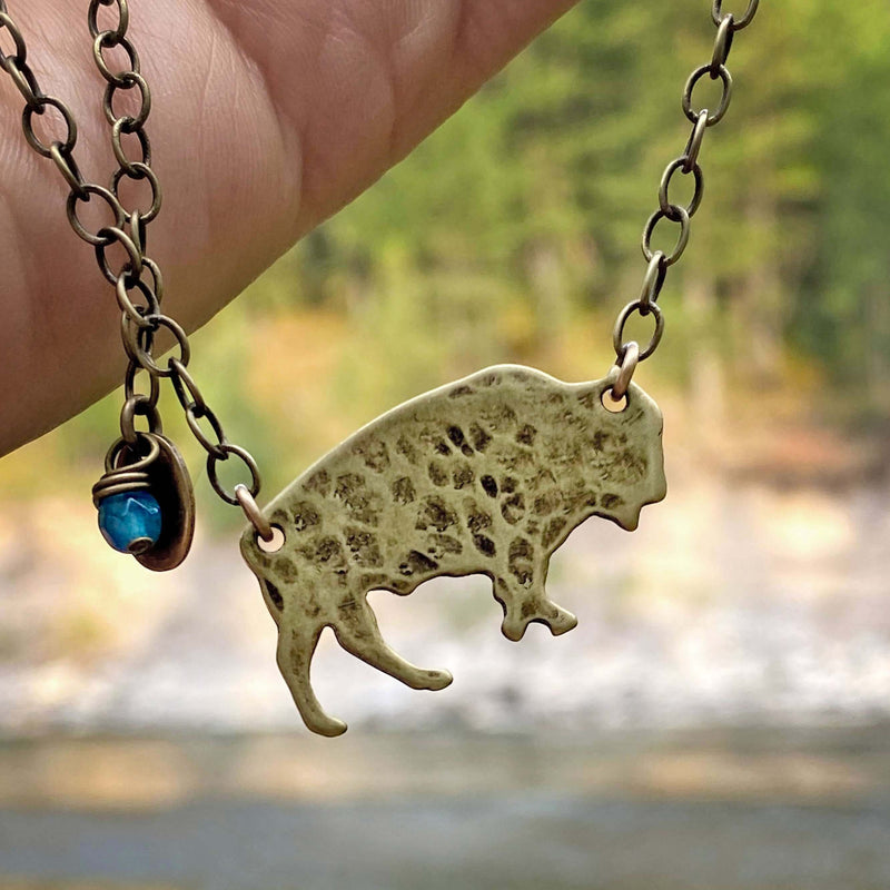 ALL THINGS BUFF bison necklace featuring a roaming buffalo design against a natural background.