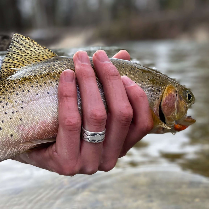 girl holding a trout fish while wearing a trout ring on her finger