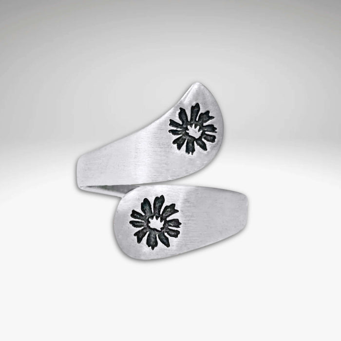 The Bitterroot Bypass Adjustable Ring is a silver wrap-around band with a brushed finish and two bitterroot flower designs at each end.