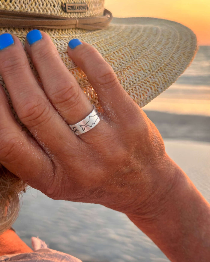 Fishing Adjustable Ring worn by a person by the beach at sunset, showcasing its design and matte silver finish.