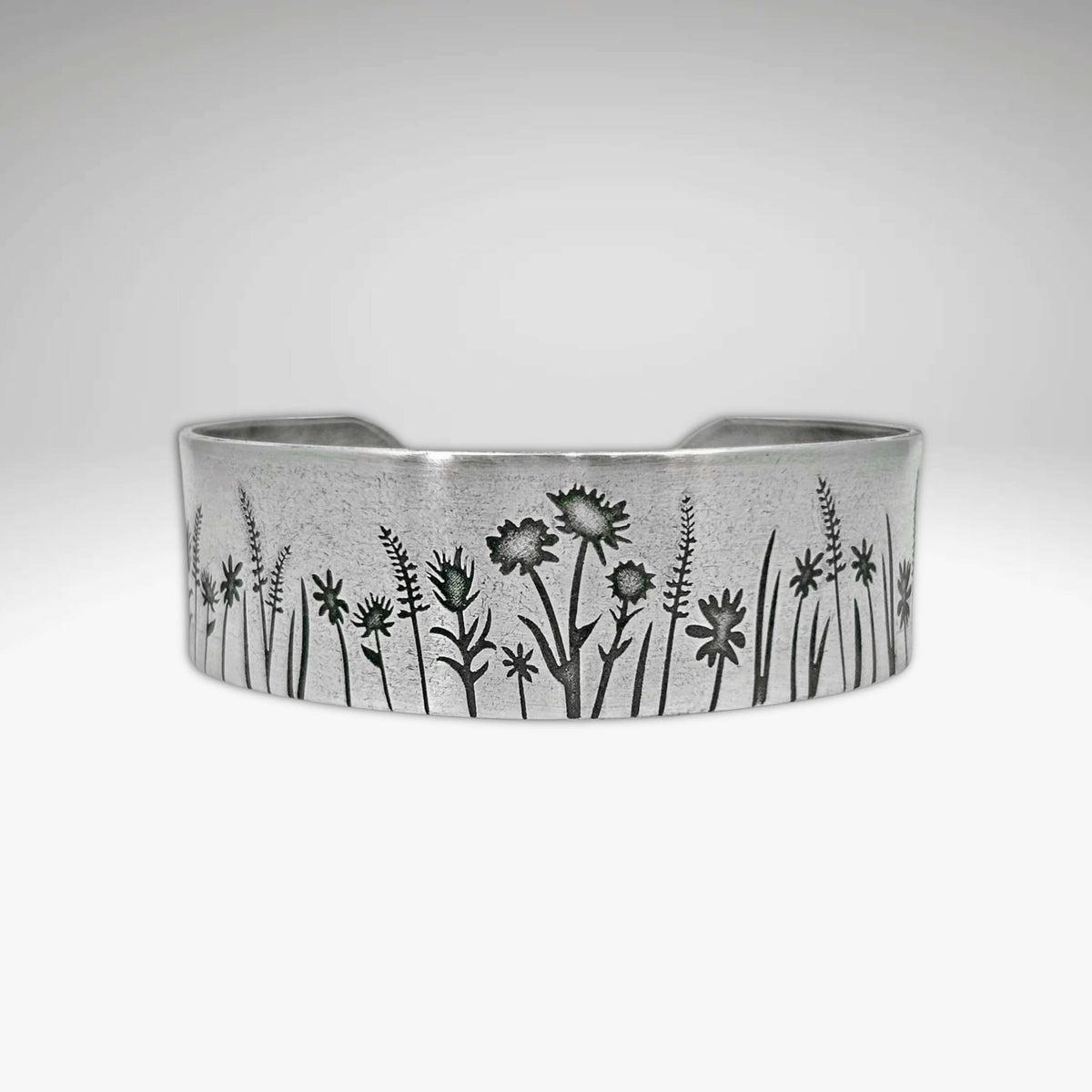 The Wildflowers Cuff is a silver bracelet etched with wildflowers and grasses.