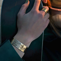 Steelhead Cuff Bracelet featuring an engraved steelhead design in antique brass on a women's wrist
