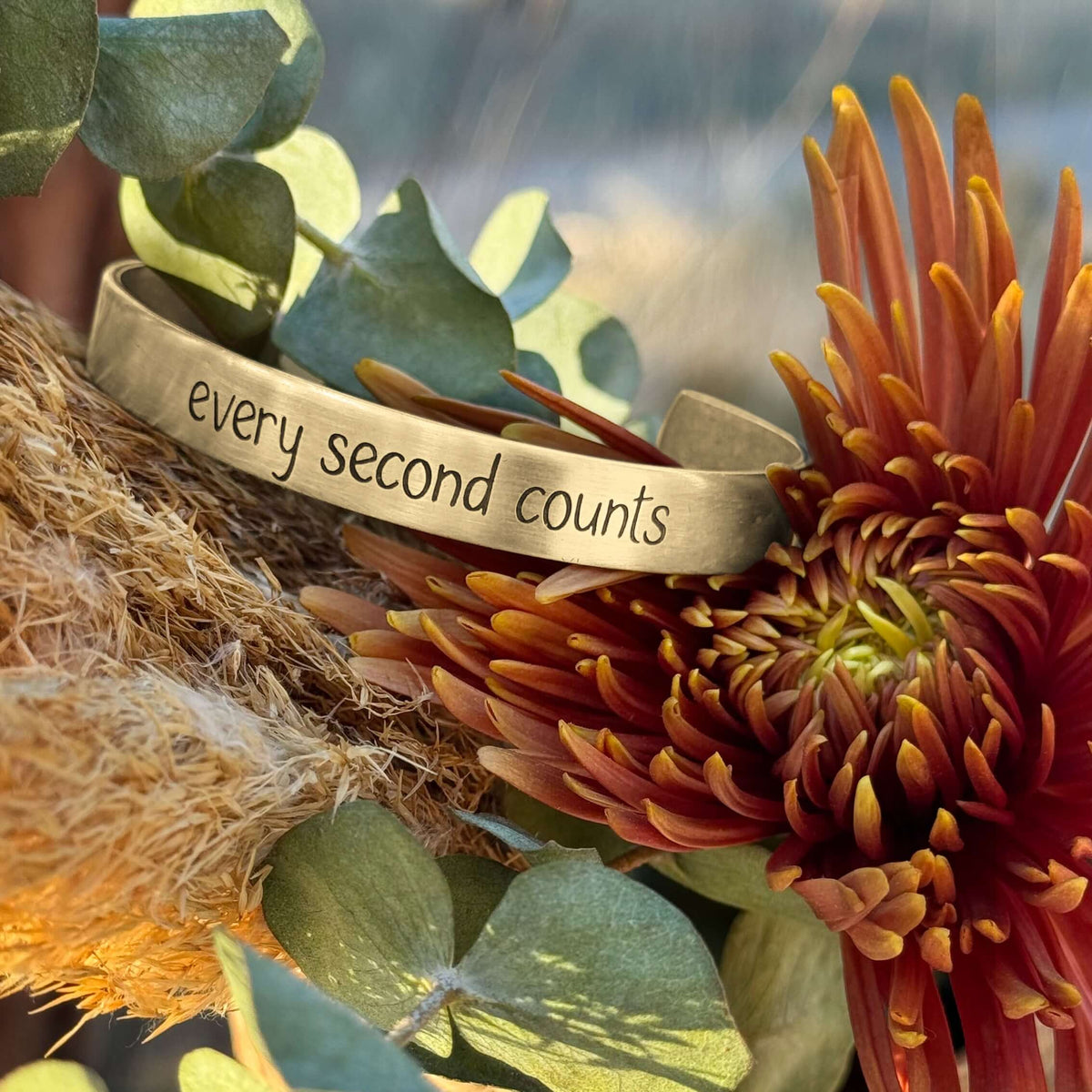 Every second counts - Bear Cuff Bracelet showcased with vibrant flower backdrop.