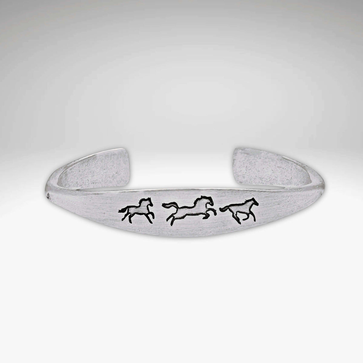 Wild Horses cuff bracelet in matte silver with three galloping horse designs, a timeless and elegant accessory.
