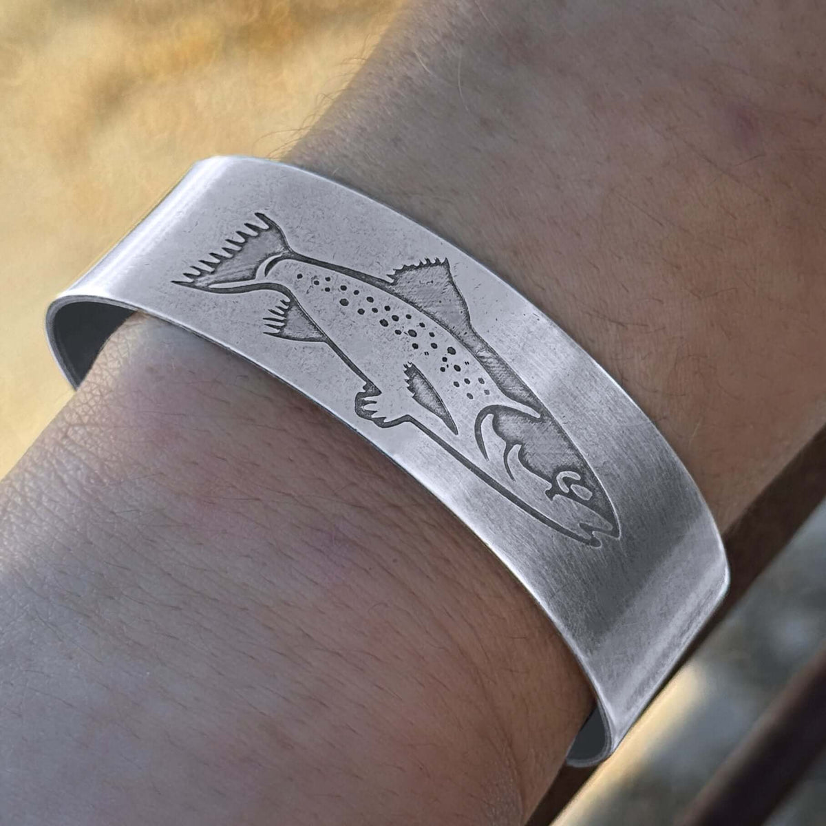 Matte Silver Steelhead Cuff Bracelet featuring an engraved steelhead design, closeup of womens wearing