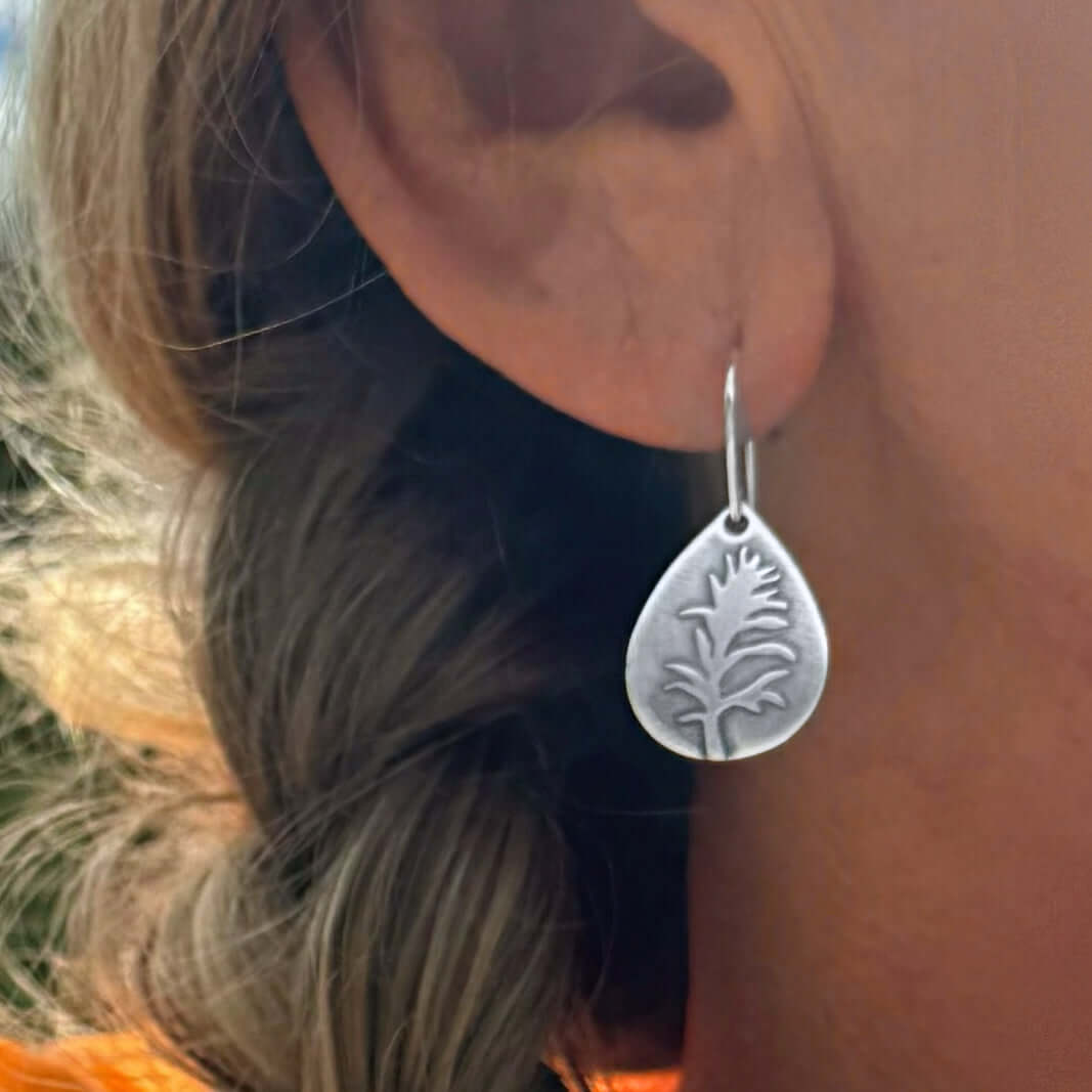 Paintbrush flower earrings in matte silver, showcasing intricate wildflower design on teardrop plate.