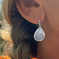 Paintbrush flower earrings in matte silver, showcasing intricate wildflower design on teardrop plate.