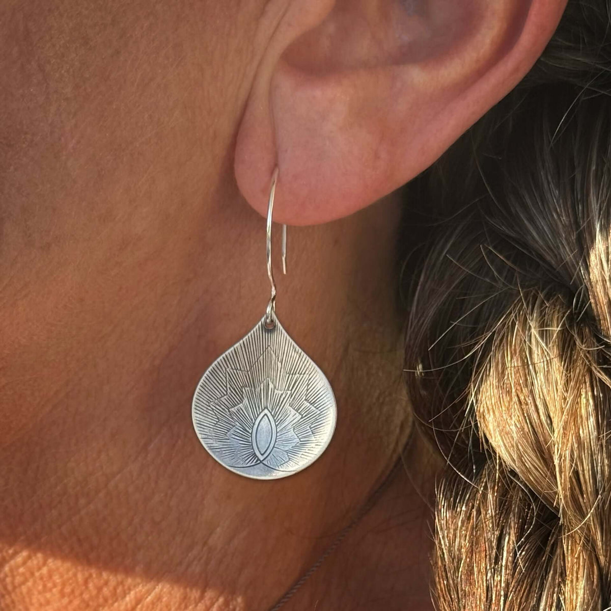 Matte Silver Petals Earrings displayed on an ear, showcasing a floral teardrop design and intricate detailing.