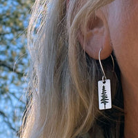Close-up of P Pine Tree Earrings hanging on ear, showcasing the Ponderosa Pine design in a silver finish.