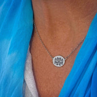 Simple Lotus Necklace featuring etched lotus design on a small raw brass oval pendant with a matte silver finish.