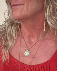 Woman wearing Bitterroot Necklace with a floral pendant, showcasing the necklace's delicate design.
