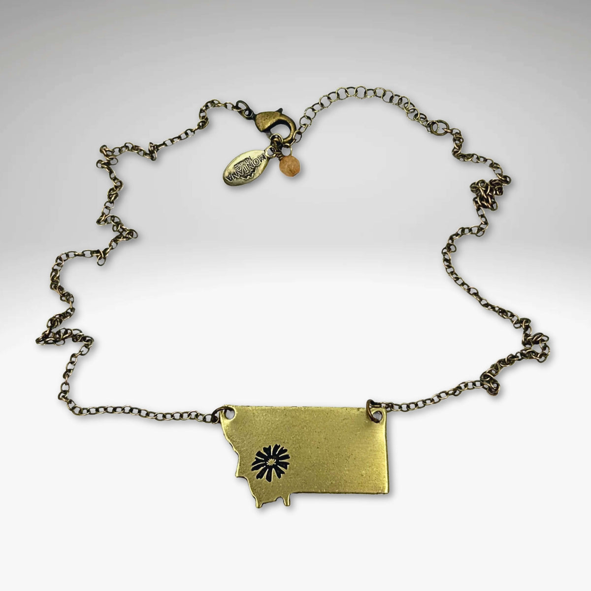 Montana outline pendant with a Bitterroot flower in antique brass on a gold plated 18" chain.