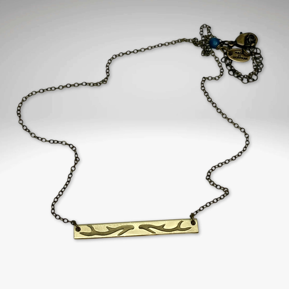 Antler Bar Necklace featuring a sleek design with a unique etching, adjustable chain and available in Matte Silver or Antique finishes.