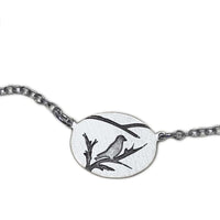 Mountain Bluebird Necklace featuring a delicate bluebird and branch design on an oval pendant.