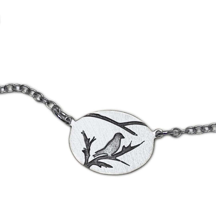 Mountain Bluebird Necklace featuring a delicate bluebird and branch design on an oval pendant.