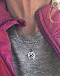 silver fox run pendant on 18" chain on a woman with a grey shirt and a pink jacket.
