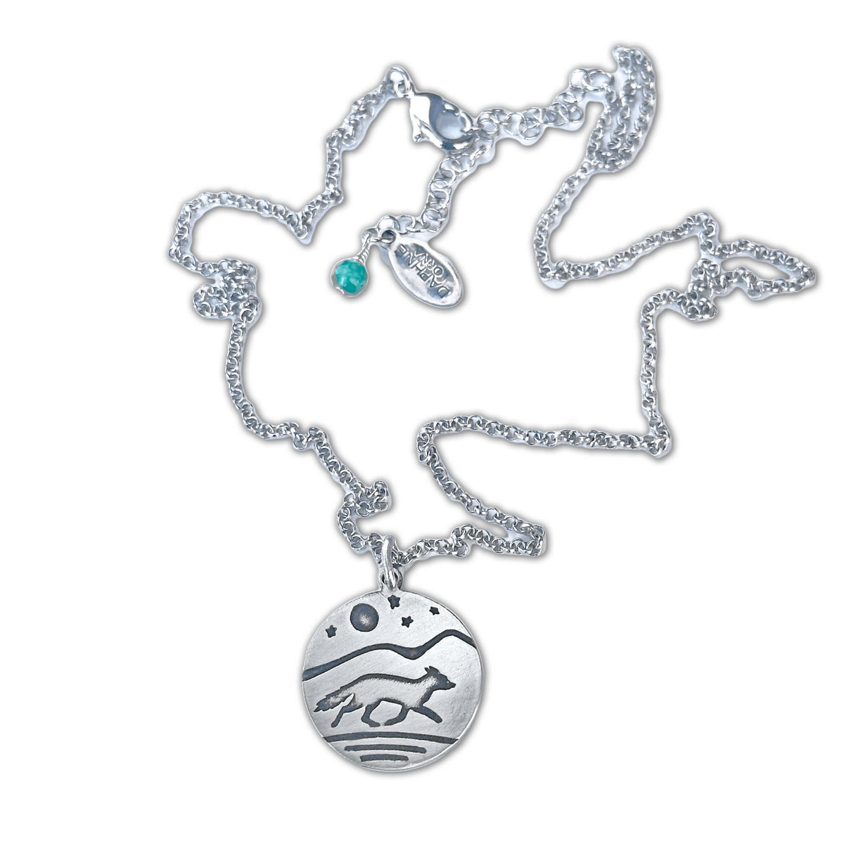 Circular pendant with a running fox and full moon, stars and a mountain background.