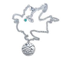 Circular pendant with a running fox and full moon, stars and a mountain background.