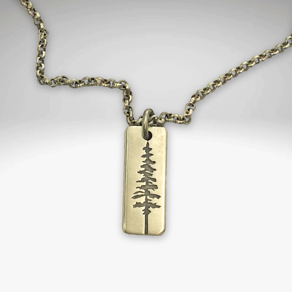 Pine Tree Necklace featuring a pendant design inspired by the Ponderosa Pine, available in Matte Silver and Antique Brass.