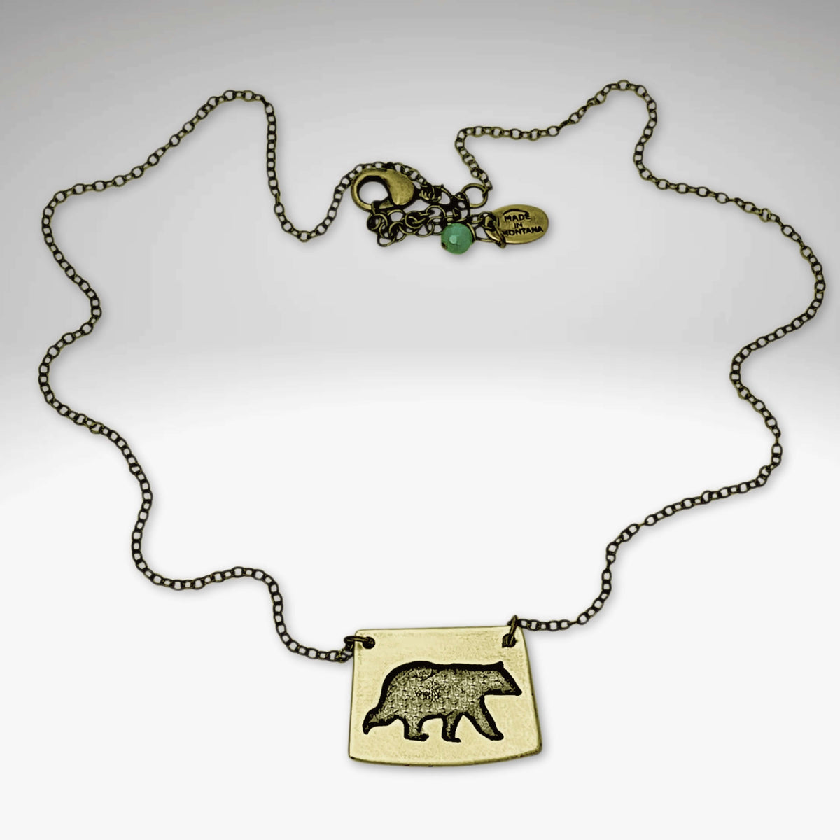 Bear Boy Necklace featuring a black bear charm on an asymmetrical rectangle pendant.