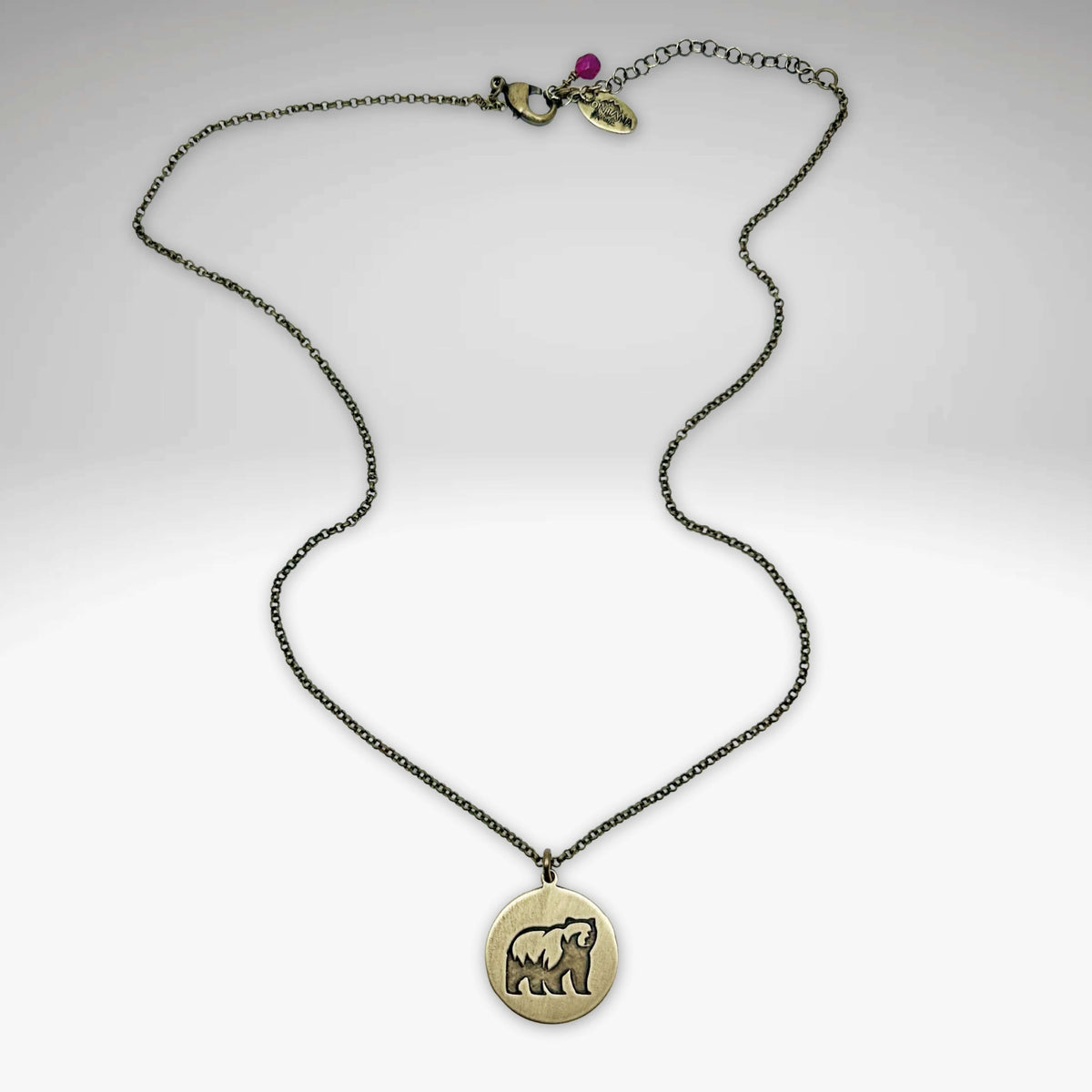 Brass round disc with a silhouette of a grizzly bear on a simple chain