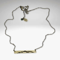 Mountainscape Necklace featuring a raw brass bar with etched mountain silhouette on an adjustable chain.