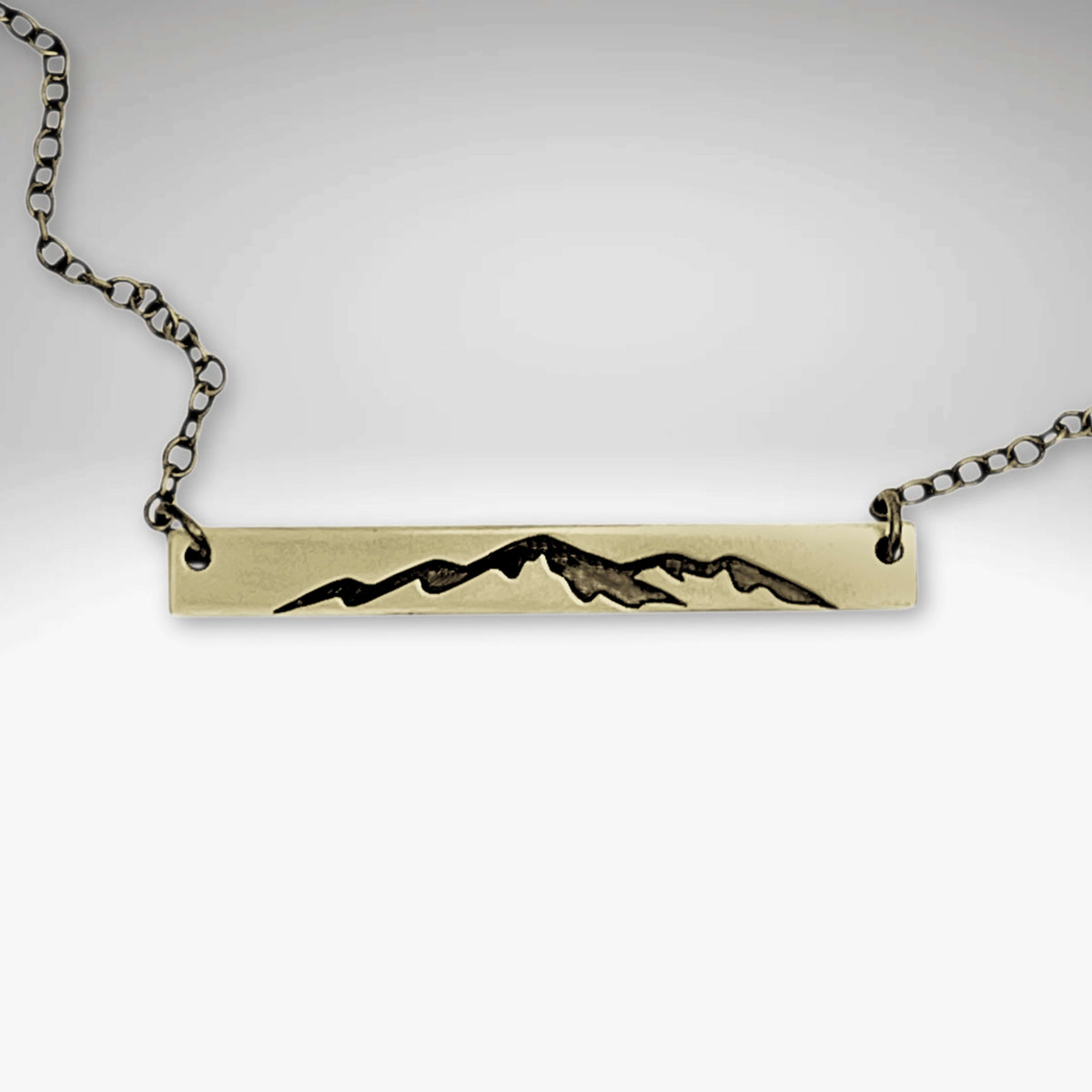 Mountainscape Necklace featuring a raw brass bar with an etched mountain silhouette, adjustable cable chain.