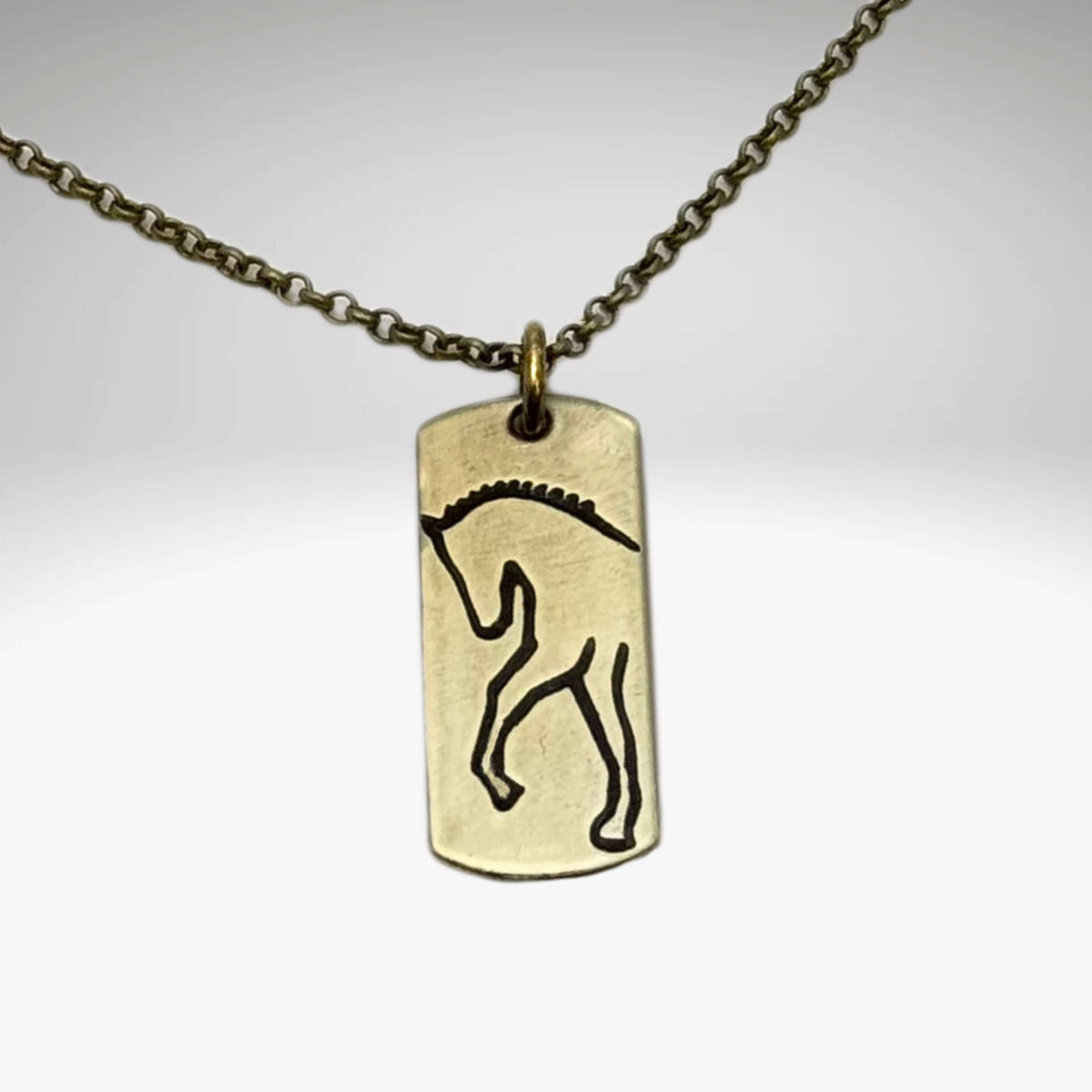 White Horse Necklace on a dainty chain, featuring a designed silhouette etched on raw brass.