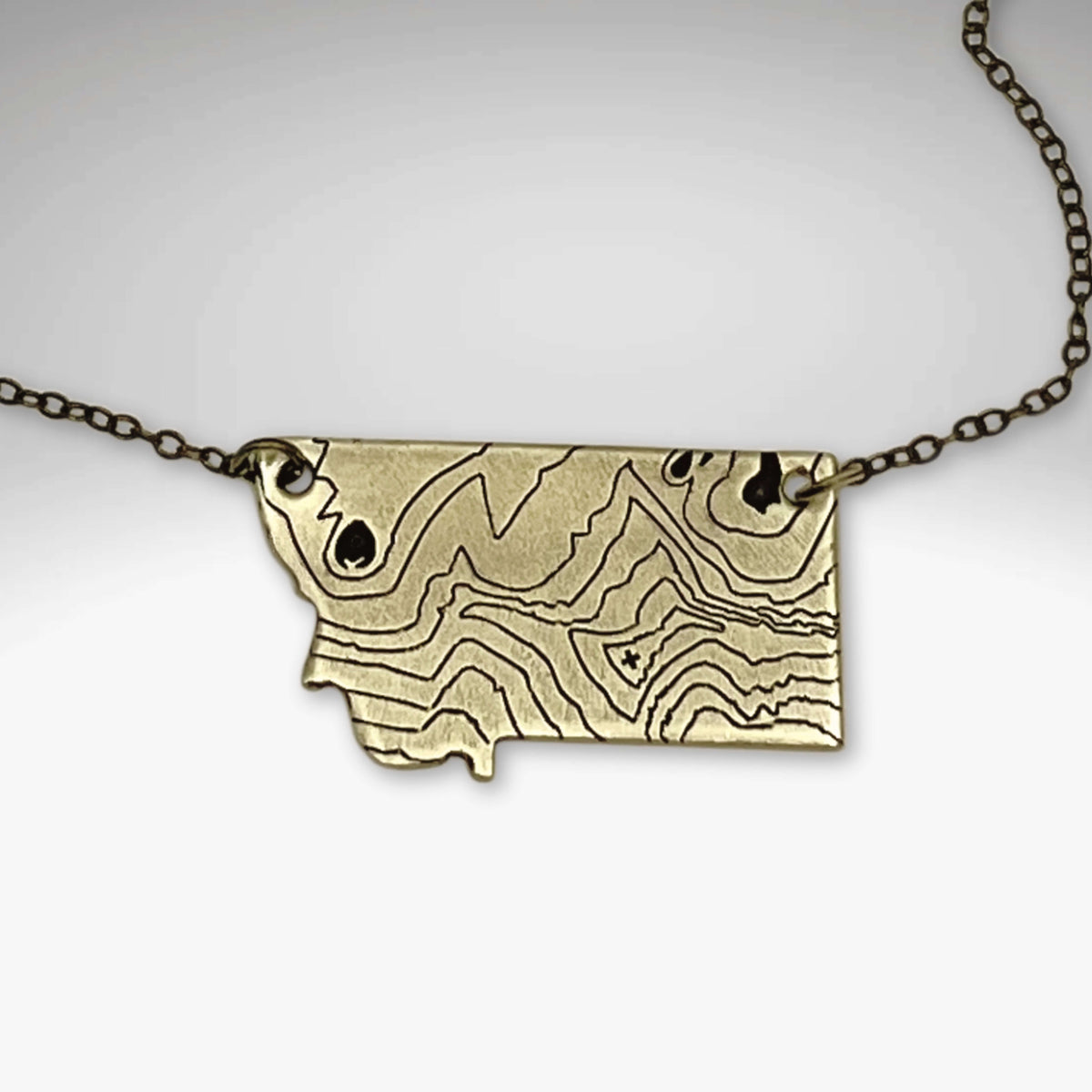 Rising Wolf MT Necklace - Topo Montana featuring a topographic design of Montana mountains.