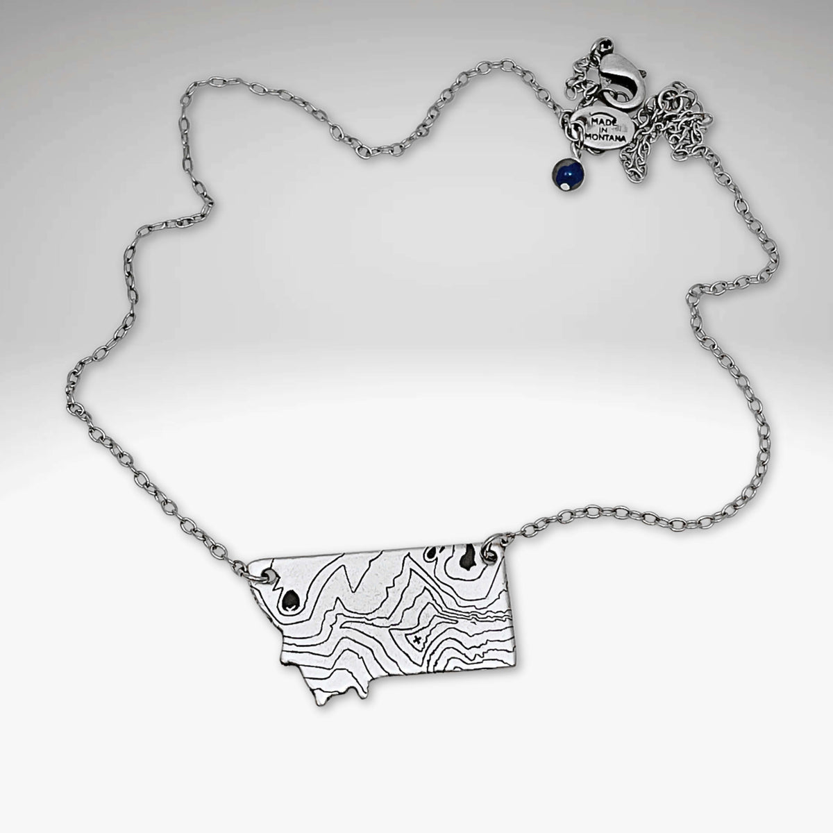 Rising Wolf MT Necklace - Topo Montana with topographic design of Montana mountains and a rising wolf.