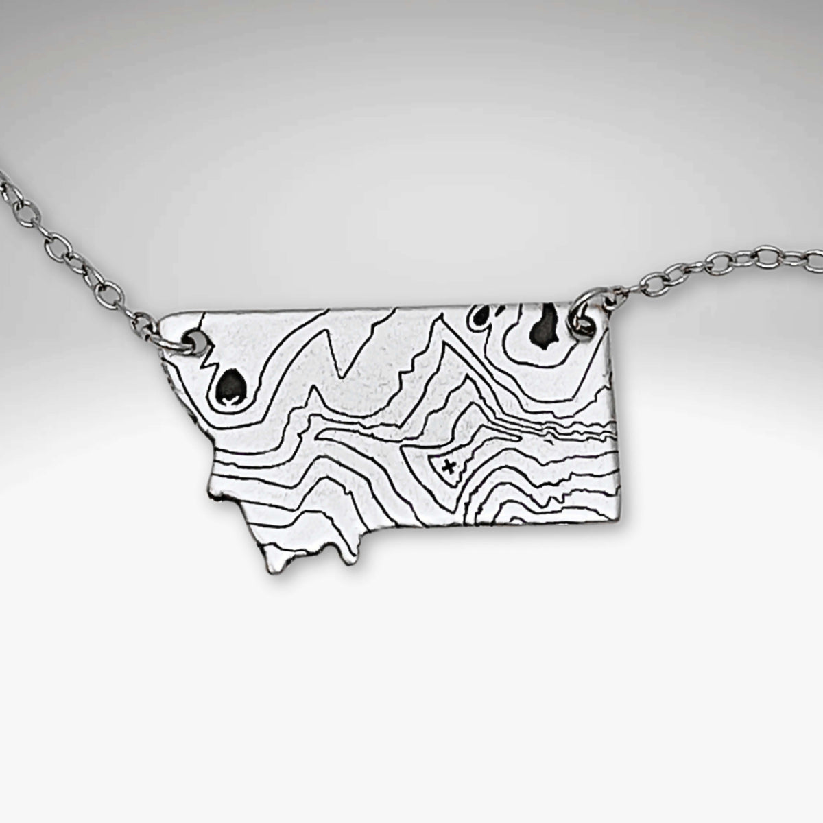 Rising Wolf MT Necklace - Topo Montana featuring a topographic design of Montana mountains.