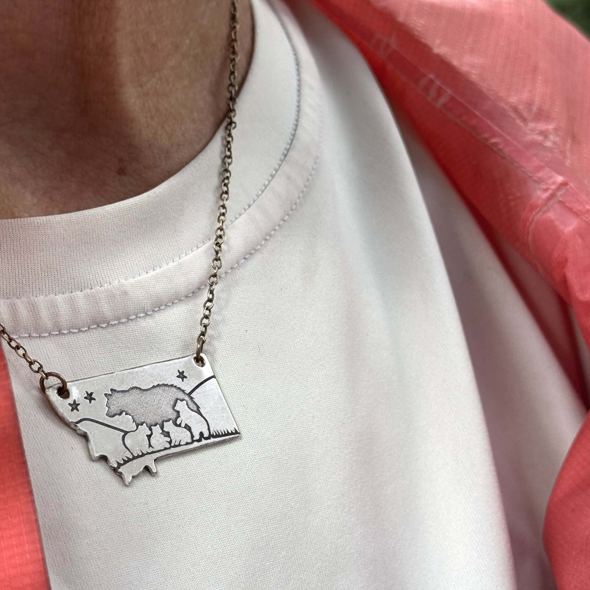 Four Cubs - Montana Bear Necklace in matte silver, showing bear design on adjustable chain worn with a white shirt.