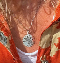 Silver pendant with a cowgirl on a horse with a lasso in matte silver on a woman with a red shirt
