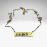 Snowfall Necklace featuring a snowflake bar design on antique brass adjustable chain.