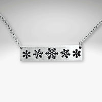 Snowfall Necklace featuring a silver bar with intricate snowflake design on a chain, perfect accessory for winter lovers.