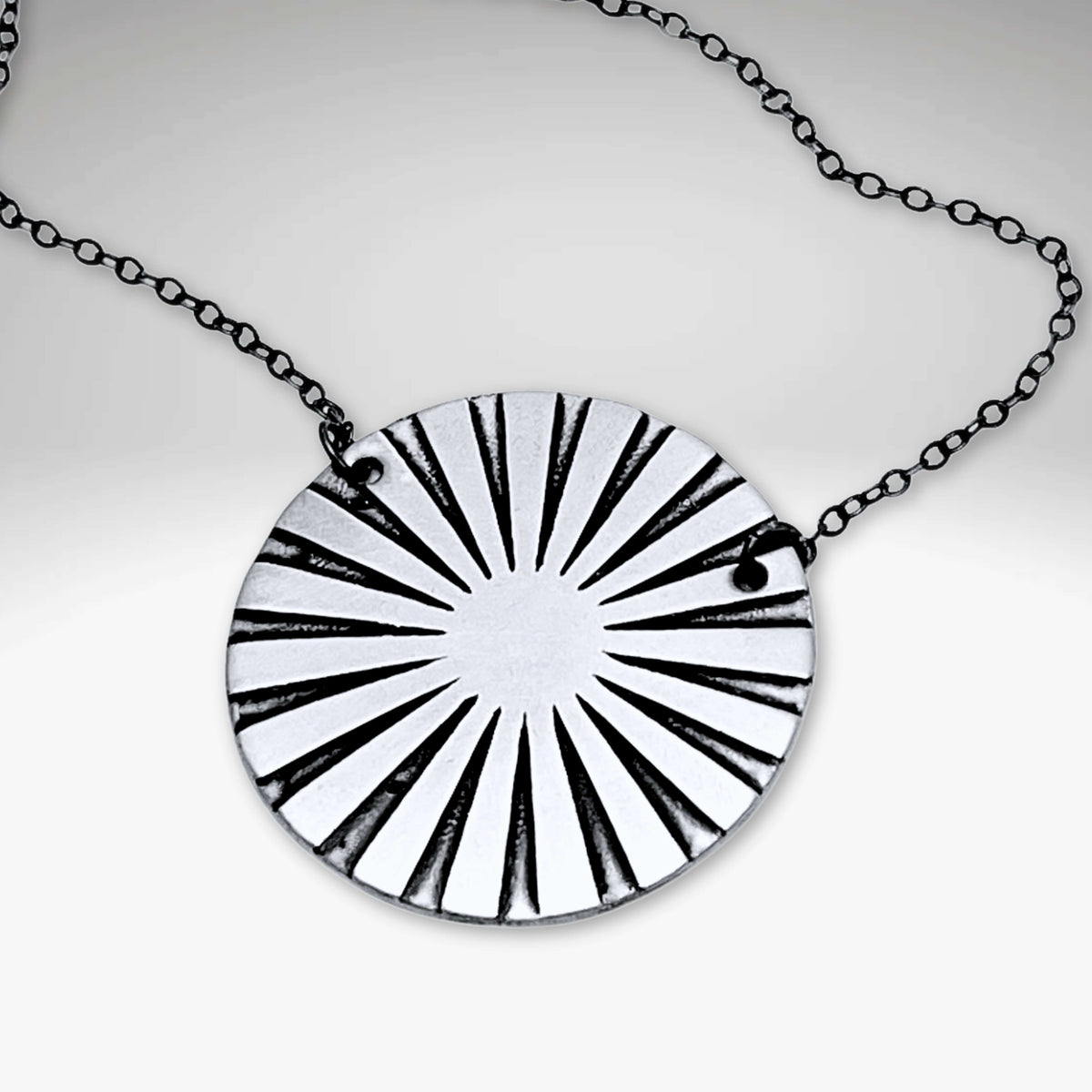 Ray Necklace featuring a sun ray design pendant on a black chain, adding a luminous effect to any ensemble.