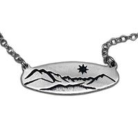 Glacier View Necklace featuring a hand-engraved mountain design in matte silver, showcasing a star detail.