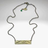 Mountain goat necklace in antique brass finish on a delicate chain with green accent bead, perfect for nature lovers.