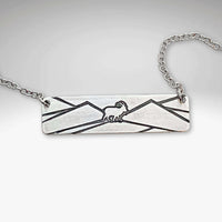 Mountain goat necklace in matte silver on a rolo chain, showcasing a minimalist mountain design.