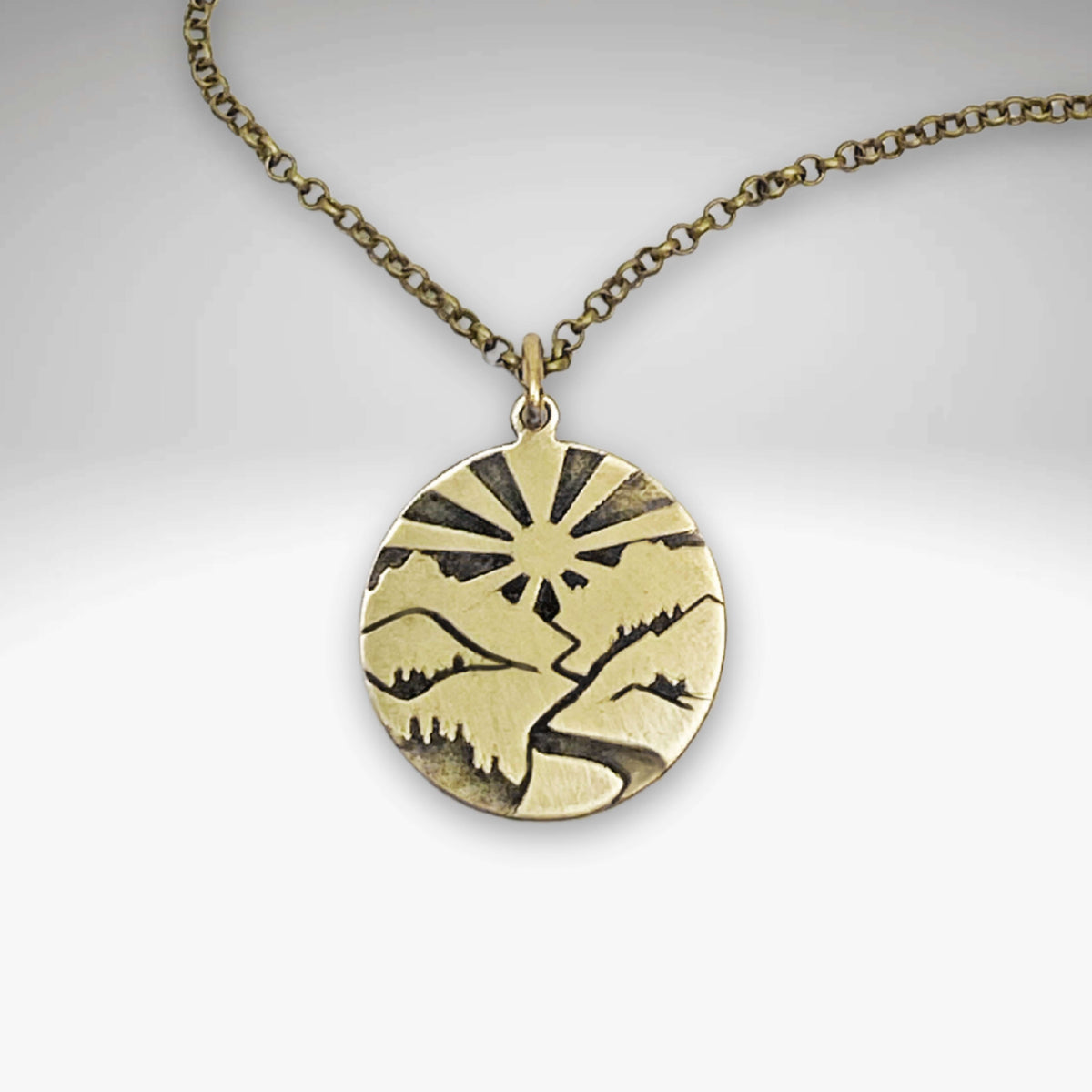 Going to the Sun Necklace featuring a mountain pendant with sunburst design on an antique brass chain.