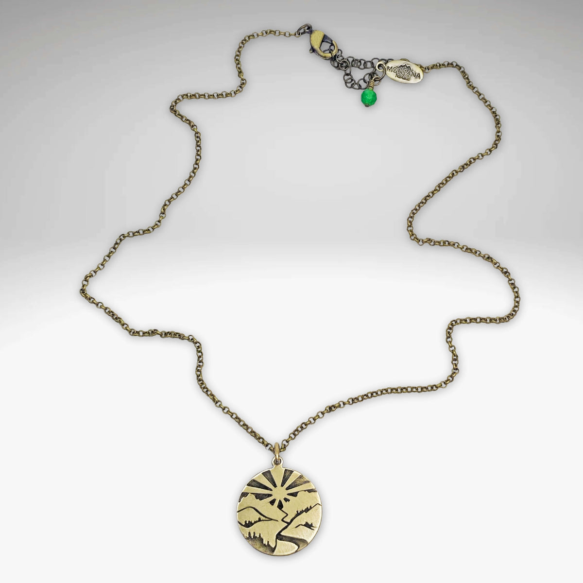 Going to the Sun Necklace featuring a mountain pendant with sunburst design on an antique brass chain.