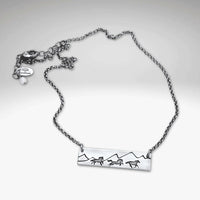 Wild Horses Necklace featuring etched mountains and mustangs on a silver chain, symbolizing freedom and the wild west.