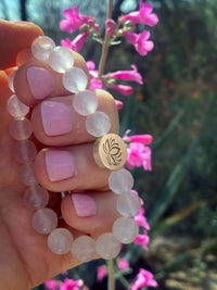 Lotus Stretch Bracelet - Gemstone Beaded Stretchy Bracelet with rose quartz beads and floral emblem in a hand.