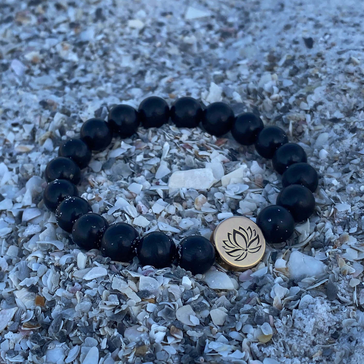 Lotus Stretch Bracelet - Gemstone Beaded Stretchy Bracelet featuring black beads on a sandy surface.