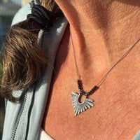 Close-up of a woman wearing the Sunbeam Necklace with hematite beads on a delicate silk cord.
