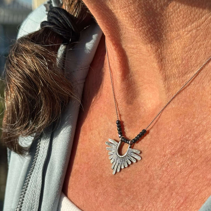 Close-up of a woman wearing the Sunbeam Necklace with hematite beads on a delicate silk cord.