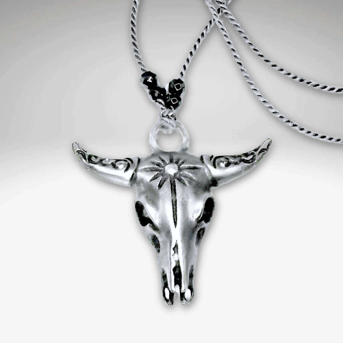 Bison skull necklace on delicate silk cord with hematite beads, available in matte silver finish.