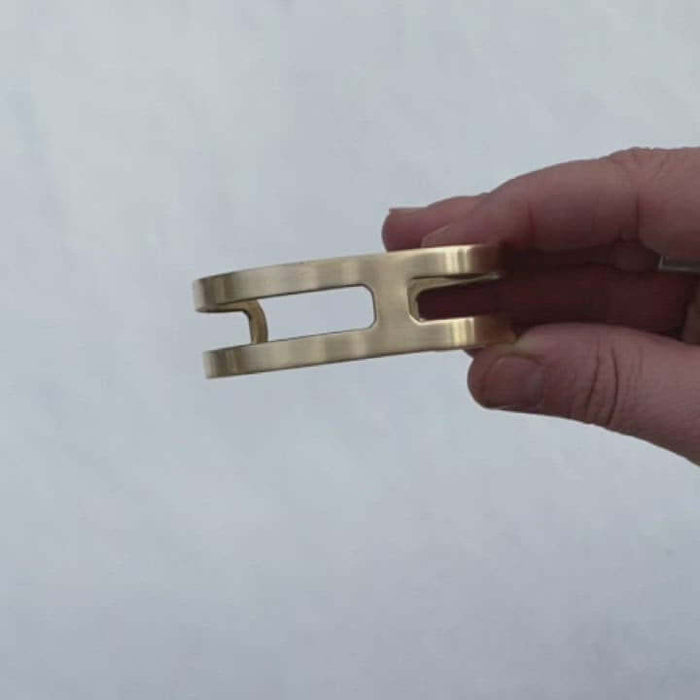 Wide Open Cuff Bracelet in antique brass held in hand, showcasing its minimalist design and adjustable fit.