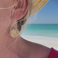 Rising Wolf Earrings featuring topographic design, worn against a beach background.