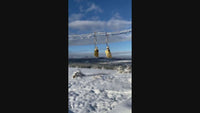 MT Beaded Hoop Earrings hanging against a snow-covered backdrop, showcasing Montana-themed jewelry design.